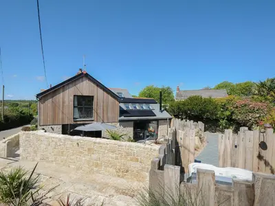 a house with a fence and a building at Stargazy Cottage in Penzance