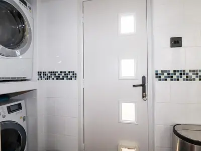 a white shower door in a bathroom with a washing machine at Pasadena in Newquay
