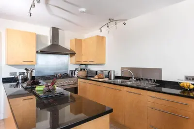 a kitchen with black counter tops and wooden cabinets at 4 The Vista, Wi-Fi, Pet Friendly in Newquay