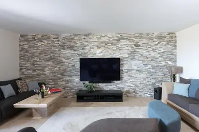 a living room with a tv and a brick wall at 4 The Vista, Wi-Fi, Pet Friendly in Newquay