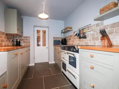 a kitchen with white appliances and a brick wall at Still Waters in St Austell