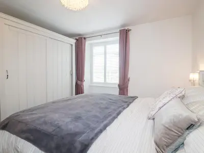 a bedroom with a bed with a large window at Still Waters in St Austell