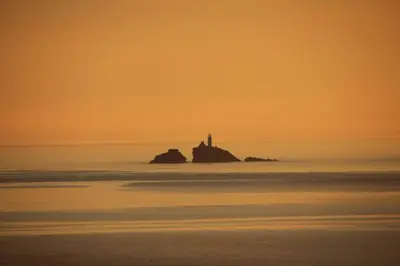 a lighthouse on a rock in the ocean at sunset at Shoreline - one of the best views? in Carbis Bay