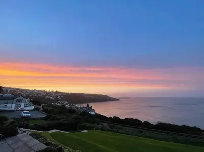 a view of the ocean at sunset with a house at Shoreline - one of the best views? in Carbis Bay