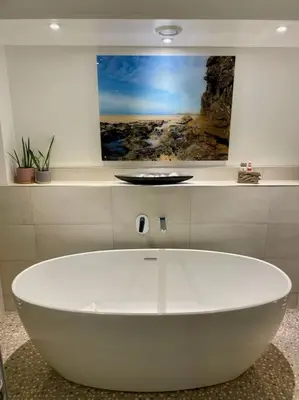 a white tub in a bathroom with a painting on the wall at Shoreline - one of the best views? in Carbis Bay