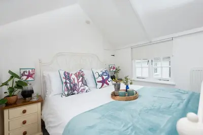 a bedroom with a large white bed with pillows at Shell Cottage, St Ives in St Ives