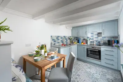 a kitchen with blue cabinets and a wooden table at Shell Cottage, St Ives in St Ives