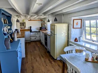 a kitchen with a refrigerator and a table in it at Foxglove Cottage in Launceston