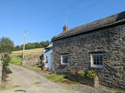 a stone house with flowers in front of it at Foxglove Cottage in Launceston