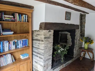 a stone fireplace in a living room with books at Foxglove Cottage in Launceston