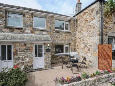 a stone house with a patio in front of it at Wheal Charlotte Cottage in Penzance