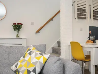 a living room with a gray couch and yellow chairs at Wheal Charlotte Cottage in Penzance