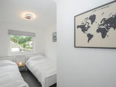 a room with two beds and a world map on the wall at Wheal Charlotte Cottage in Penzance