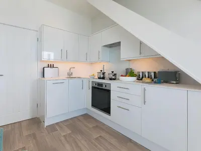 a white kitchen with white cabinets and appliances at Samphire in St Ives
