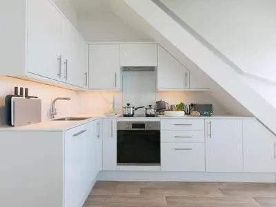 a white kitchen with white cabinets and a sink at Samphire in St Ives