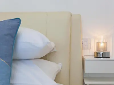 a bed with white pillows and a lamp on a table at Samphire in St Ives