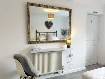 a mirror on a wall with a radiator and a chair at The Cottage Annex in Newquay