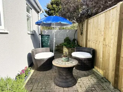 a patio with a table with a blue umbrella at The Cottage Annex in Newquay