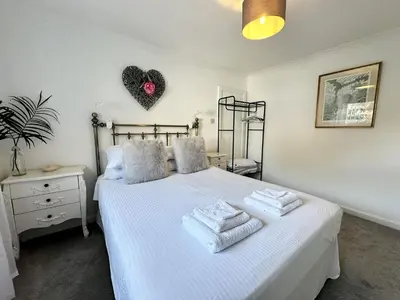 a bedroom with a white bed with towels on it at The Cottage Annex in Newquay