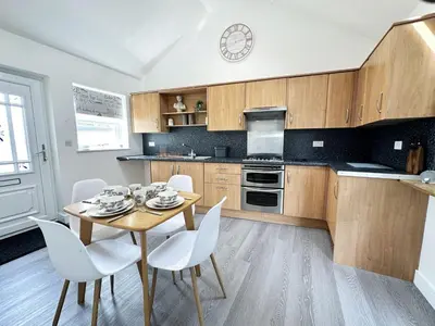 a kitchen with a table and chairs and a clock at The Cottage Annex in Newquay