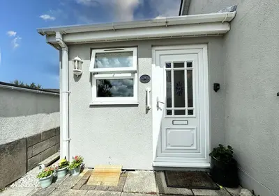 a white door of a house with potted plants at The Cottage Annex in Newquay