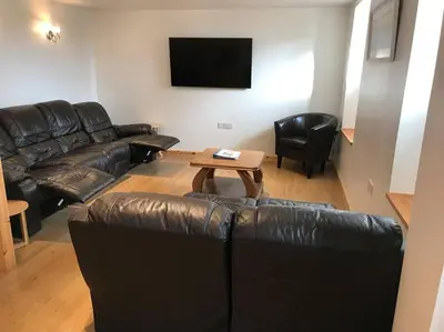 a living room with a leather couch and a table at Hendra Retreat Piglets Cottage North Cornwall in Camelford