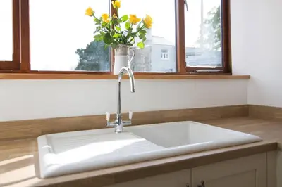a white sink in a kitchen with a vase of flowers at Hendra Retreat Piglets Cottage North Cornwall in Camelford