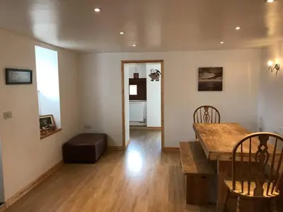 a living room with a wooden table and a couch at Hendra Retreat Piglets Cottage North Cornwall in Camelford