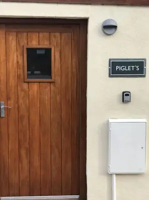 a wooden door to a building with a sign on it at Hendra Retreat Piglets Cottage North Cornwall in Camelford