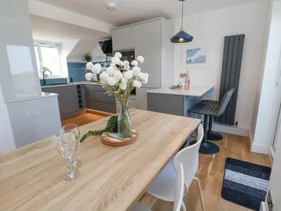 a vase of flowers on a wooden table in a kitchen at Island View in Newquay