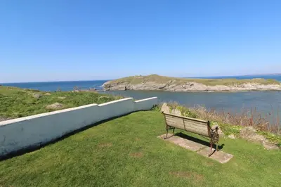 a bench sitting on the grass near the water at Island View in Newquay