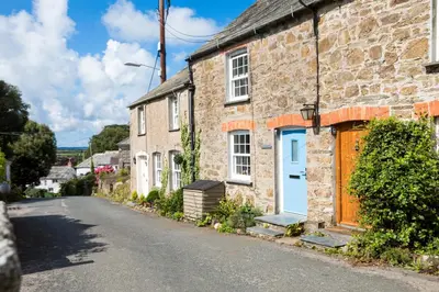 a stone house with a blue door on a street at Stokes Cottage in Wadebridge