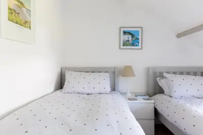 a bedroom with two beds and a night stand at Stokes Cottage in Wadebridge