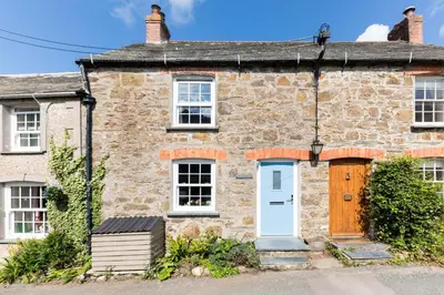 an old stone house with a white door at Stokes Cottage in Wadebridge