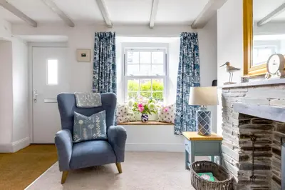 a living room with a blue chair and a window at Stokes Cottage in Wadebridge
