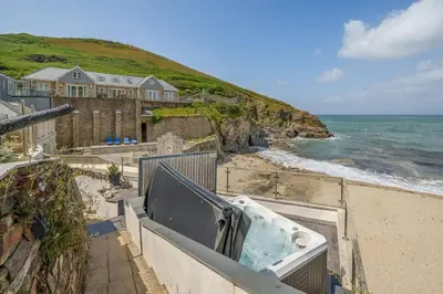 a bath tub sitting on a wall next to the ocean at Award Winning 5* BEACH HOUSE! Hot Tub & Fire Pit in Portreath