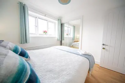 a white bedroom with a bed and a window at Trethvor House FREE PARKING Private bathroom Double in Padstow