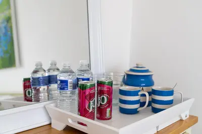a shelf with water bottles and cups on it at Trethvor House FREE PARKING Private bathroom Double in Padstow