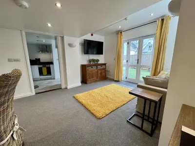 a living room with a television and a couch and a table at The Coach House - with hot tub in St Austell