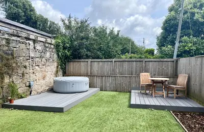 a backyard with a hot tub and two chairs and a table at The Coach House - with hot tub in St Austell