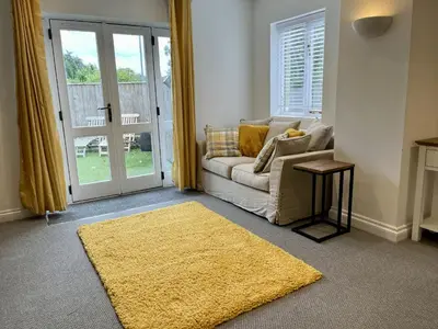 a living room with a couch and a yellow rug at The Coach House - with hot tub in St Austell