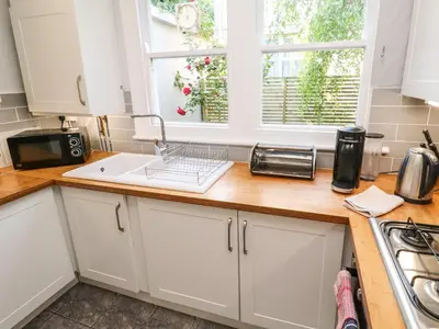 a kitchen with white cabinets and a sink and two windows at 8 Rosewall Cottages in St Ives