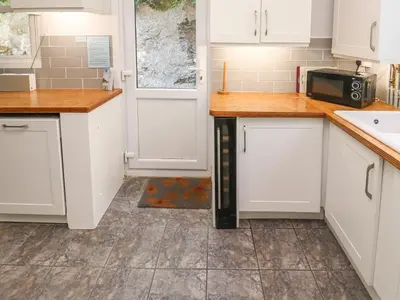 a kitchen with white cabinets and a microwave at 8 Rosewall Cottages in St Ives