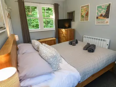 a bedroom with two beds and a flat screen tv at 8 Rosewall Cottages in St Ives