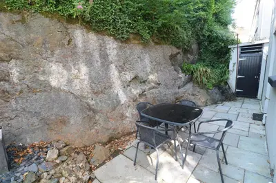 a table and chairs sitting next to a stone wall at 8 Rosewall Cottages in St Ives