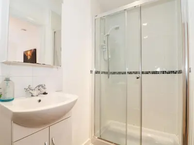 a white bathroom with a sink and a shower at Garras in Truro