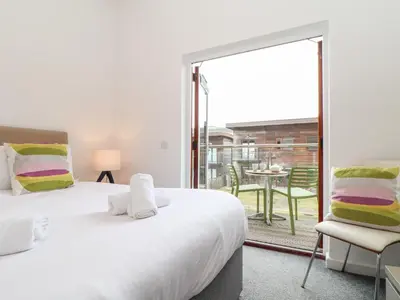 a bedroom with two beds and a balcony with a table at Garras in Truro