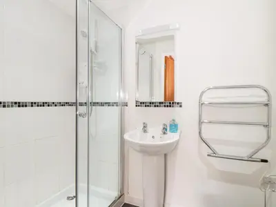 a white bathroom with a sink and a shower at Garras in Truro