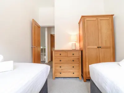 a bedroom with two beds and a wooden dresser at Tehidy in Truro