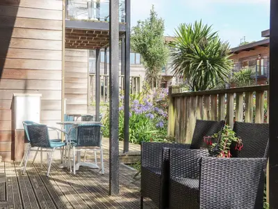 a patio with chairs and a table and a fence at Tehidy in Truro